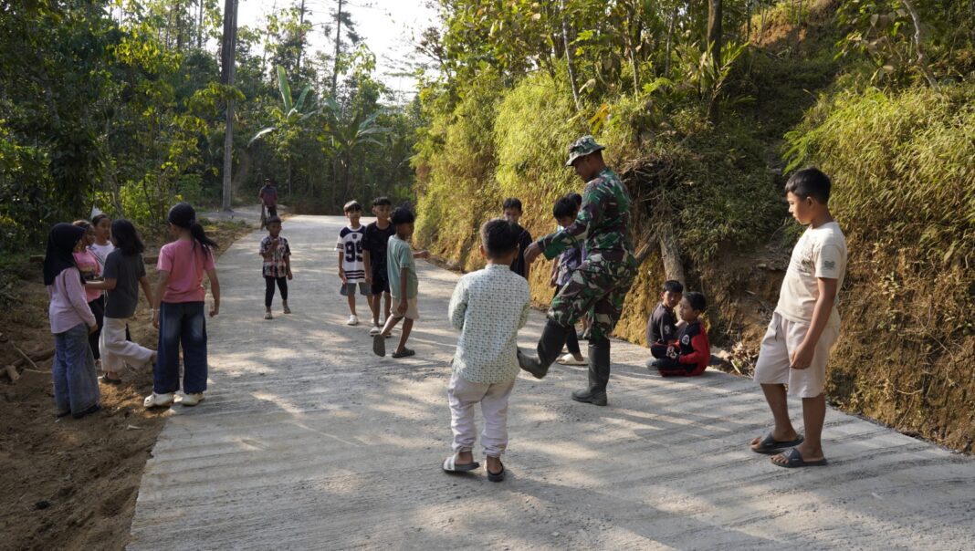 Satgas TMMD Manfaatkan Jalan Baru, Bermain Bola Bersama Anak Desa Watuduwur Satgas TMMD Manfaatkan Jalan Baru, Bermain Bola Bersama Anak Desa Watuduwur